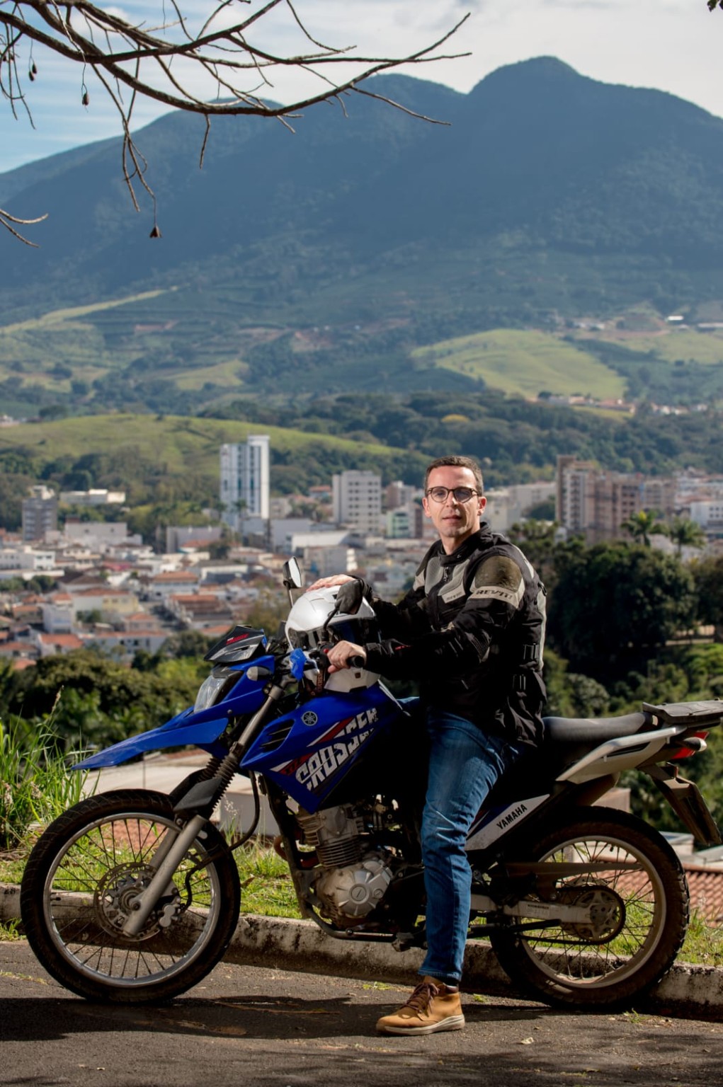 Carlos Pioli com sua moto e a cidade ao fundo